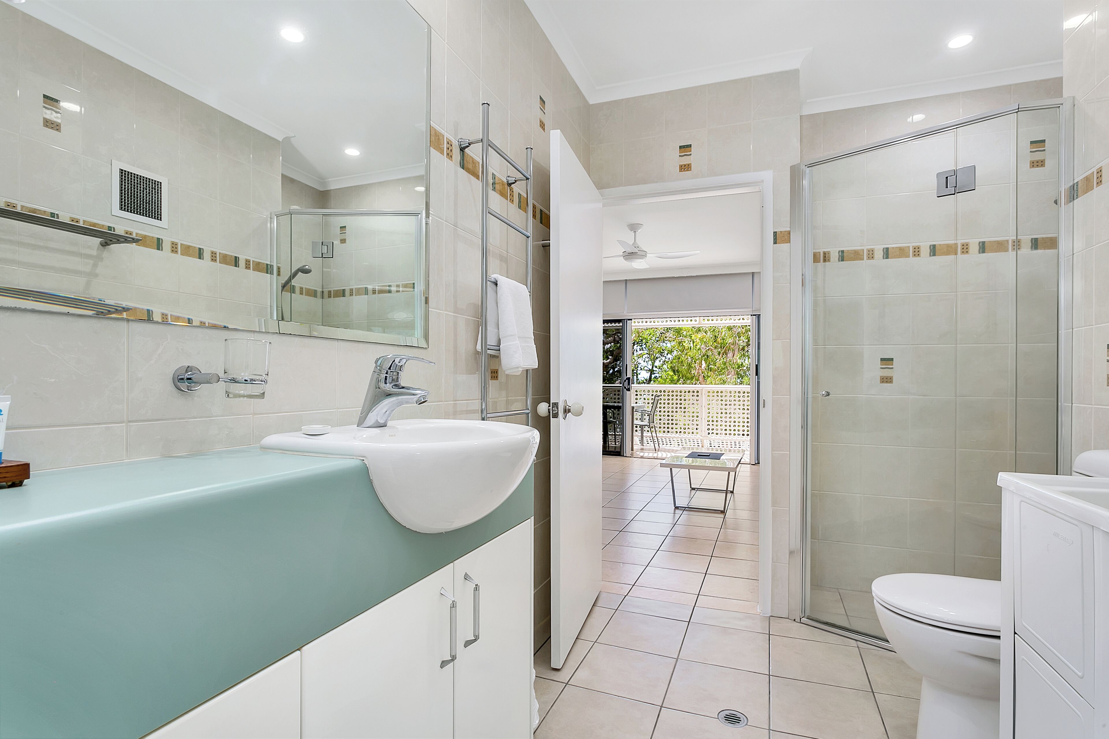 Un bany modern amb un lavabo gran, un plat de dutxa de vidre i un vàter.
