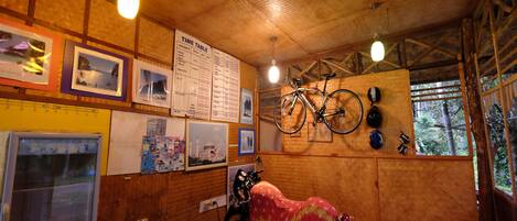 A room with a wooden ceiling, a covered motorcycle, a time table on the wall, and bicycles hanging on the wall.