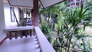 Un balcón techado con vista a un jardín y un edificio en construcción.