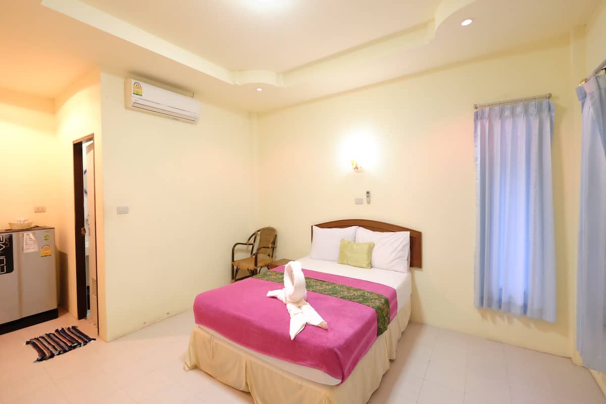 Hotelkamer met een bed, een bureau, een airconditioning, een stoel en een raam met gordijnen.