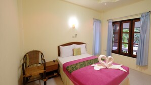 Un dormitorio ordenado con cama, una silla, una mesita de noche y una ventana con cortinas.