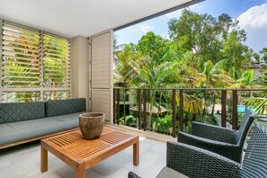 Relax on the balcony with a comfortable seating area and unobstructed views of lush tropical vegetation.