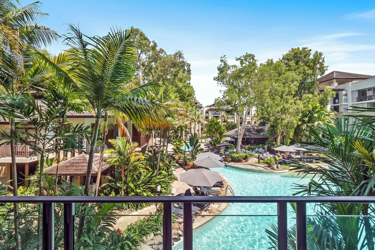 A resort with a swimming pool surrounded by palm trees and lounge chairs.