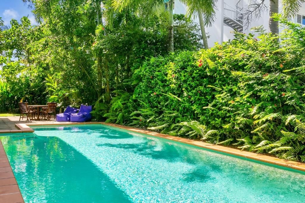 A swimming pool surrounded by lush greenery and a staircase leading to a building.