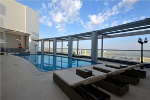 A rooftop pool with lounge chairs and a view of the city skyline. - Piks Key - Burj Al Nujoom (Dubai)