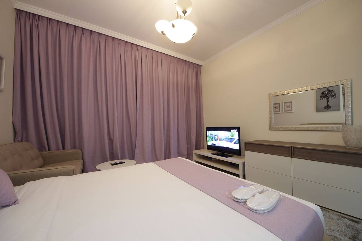 Une chambre d’hôtel équipée d’un lit, d’une télévision, d’un canapé et d’une commode.