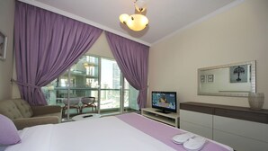 Ein Hotelzimmer mit Bett, Fernseher, Sofa und Blick auf die Stadt durch große Fenster.