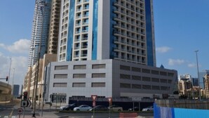 Ein hohes, modernes Gebäude mit weiß-blauer Fassade, mehreren Stockwerken und einem markanten Eingangsbereich.