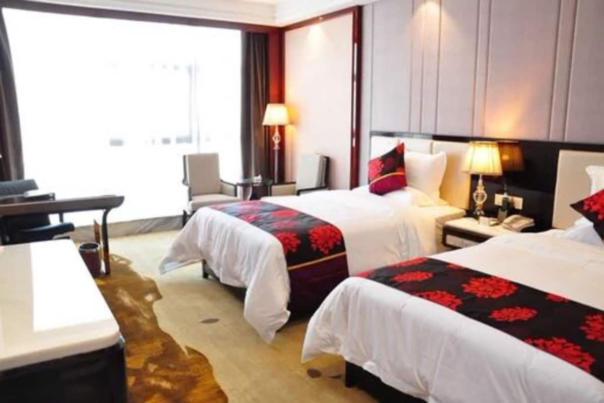 A hotel room with two beds, a desk, and a chair.