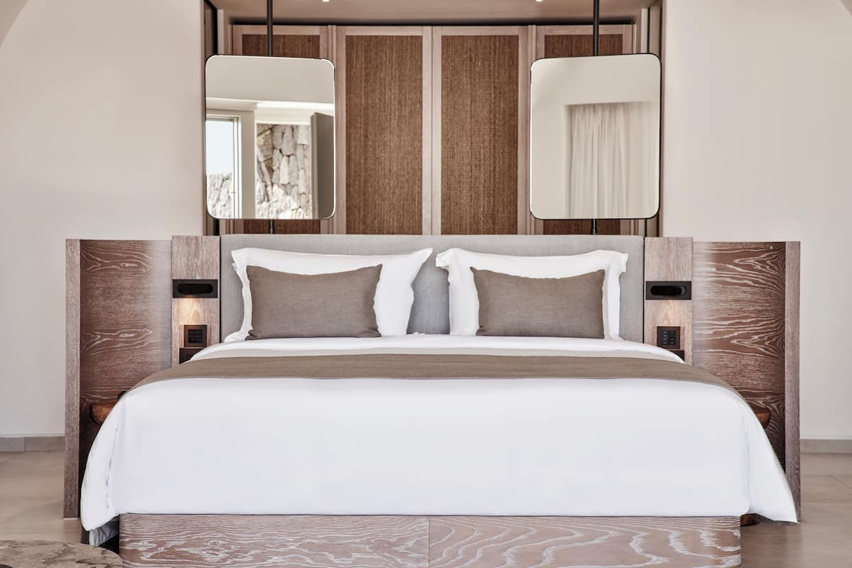 Une chambre à coucher moderne avec un grand lit, une tête de lit en bois et deux tables de chevet.