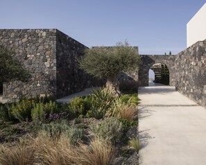 A stone-walled courtyard with a pathway leading to an archway.