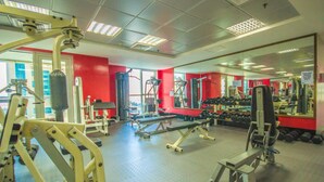 A gym with various exercise equipment, a mirrored wall, and a red accent wall.