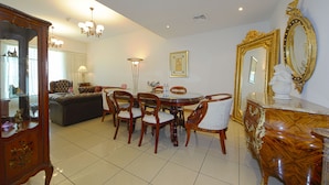 A dining area with a round table, chairs, a chandelier, and a large mirror with an ornate frame.