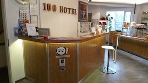 Een receptiebalie bij Hotel 100 Iceland, met een houten afwerking, een logo sticker en een bord dat aangeeft dat het een SAF-gecertificeerd hotel is.