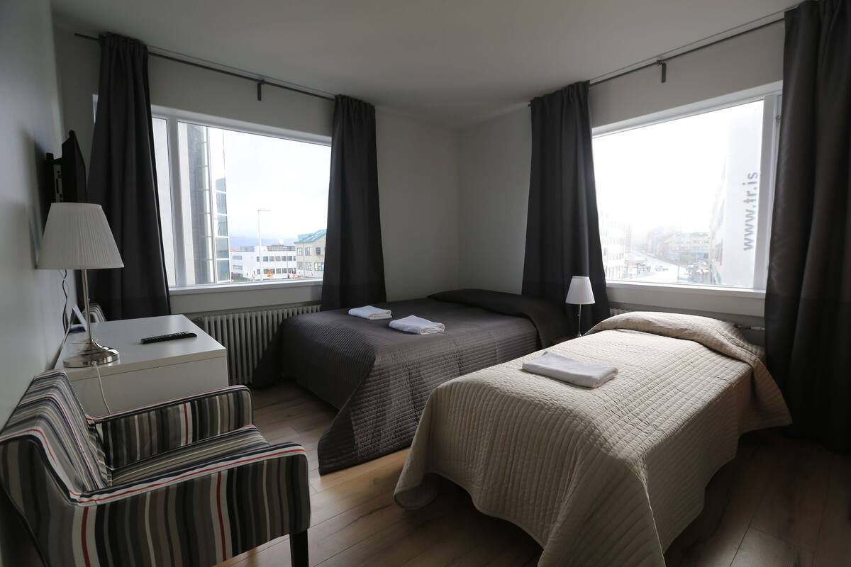 Hotellihuone, jossa on kaksi sänkyä, työpöytä ja tuoli.