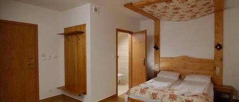 A bedroom with a wooden bed, a wooden wardrobe, and a wooden door.