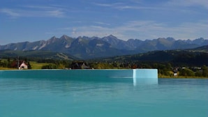 Un lago con una cadena montañosa al fondo y un edificio pequeño en la orilla.