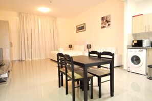 A hotel room with a dining table, chairs, a sofa, a washing machine, and a television. - Piks Key- Madison Residences (Dubai)