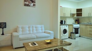 A modern living room with a white sofa, a coffee table, and a washing machine in the background.