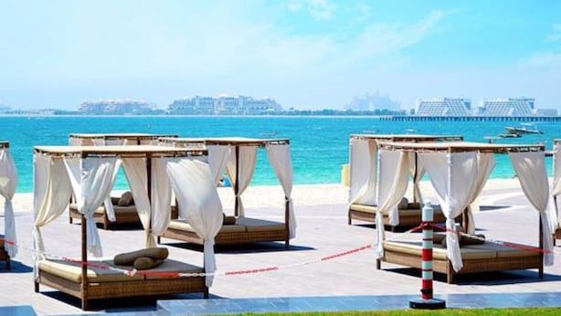 A beachside hotel with outdoor beds and a view of the sea and city skyline. - Piks Key - Sadaf 4 (Dubai)