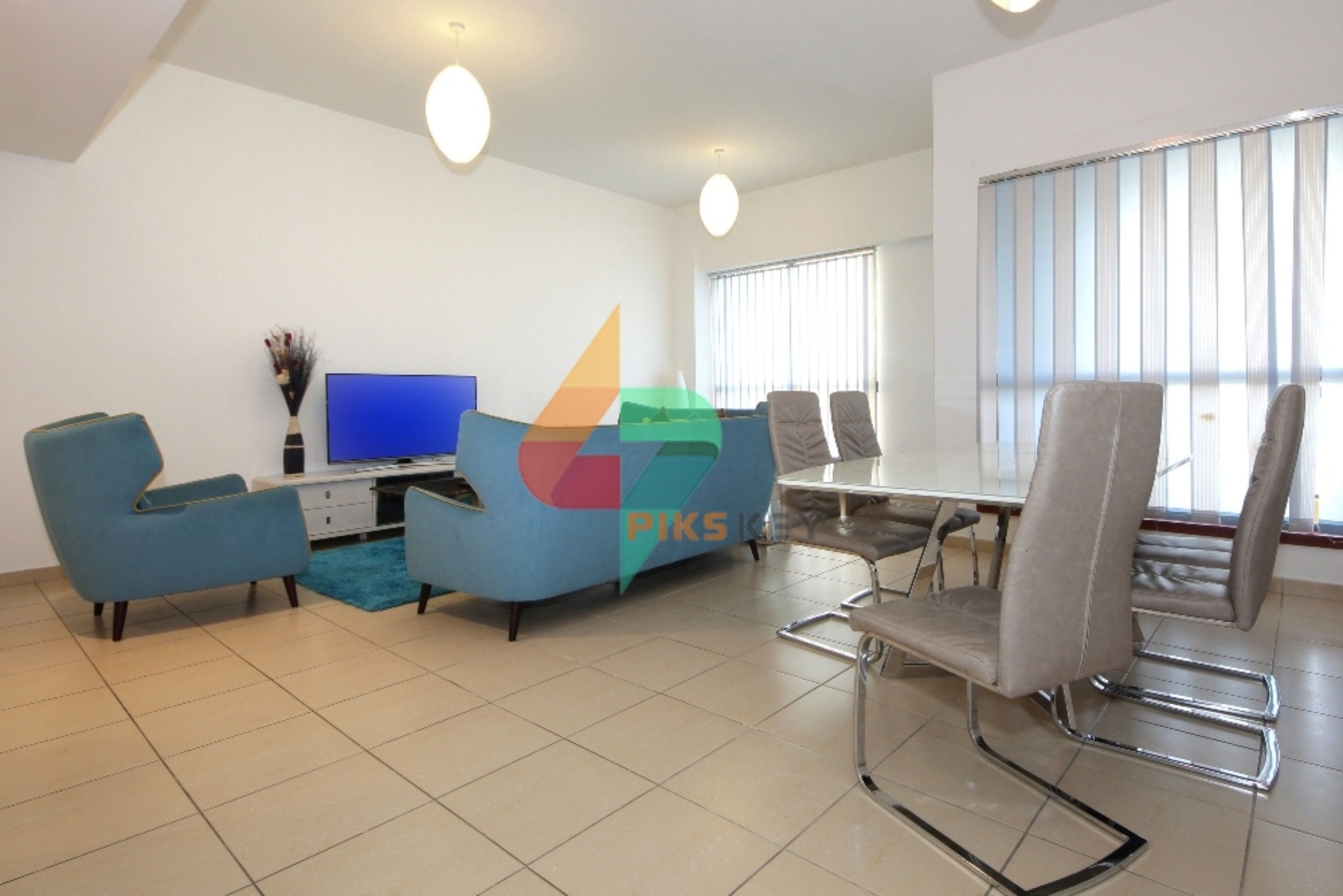 A modern living room with a TV, blue sofa, and a dining table with chairs.
