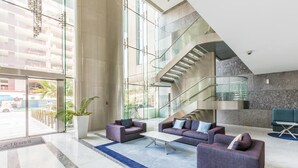 Eine geräumige Lobby mit moderner Treppe, bequemen Sitzgelegenheiten und großen Fenstern mit Blick ins Freie.