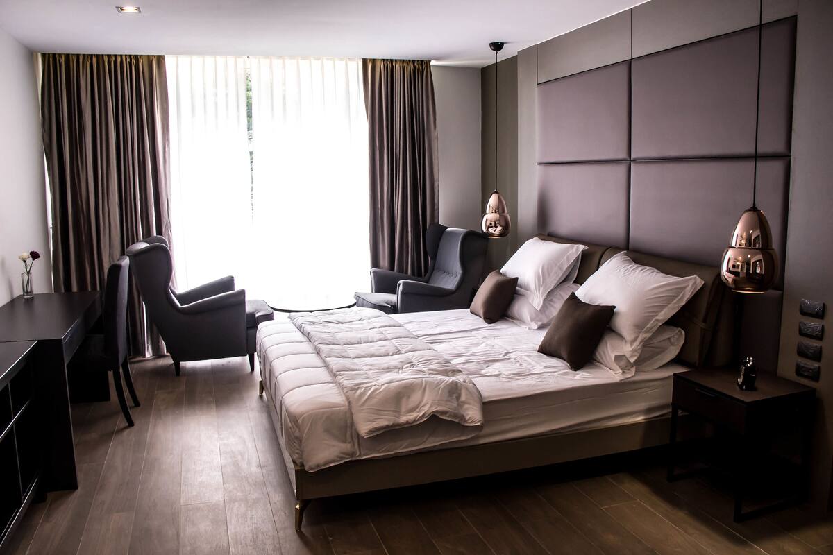 A modern hotel room with a large bed, a desk, and a chair.