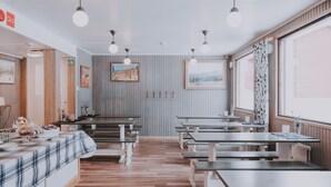 Un restaurante con mesas y bancos de madera, una barra con mantel a cuadros y cuadros en las paredes.
