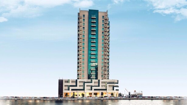 A high-rise building with multiple balconies, a modern architectural design, and a waterfront location. - Piks Key - Mayfair Residency (Dubai)