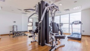 A gym with cardio machines, weightlifting equipment, and a treadmill. - Piks Key - Mayfair Residency (Dubai)