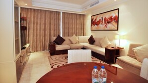 A hotel room with a sofa set, a coffee table, a TV, and a painting on the wall. - Piks Key - Grandeur Residences (Dubai)