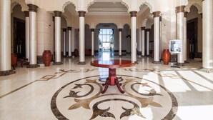 A grand lobby with a central round table, high columns, and a patterned floor. - Piks Key - Grandeur Residences (Dubai)