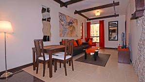 Un salon moderne avec un coin repas, comprenant un canapé, des fauteuils, une table basse et un tableau au mur.