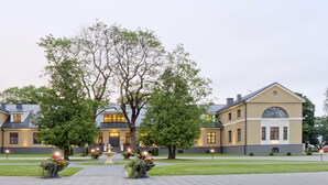 En stor, symmetrisk byggnad med en central entré, flankerad av två sidobyggnader.