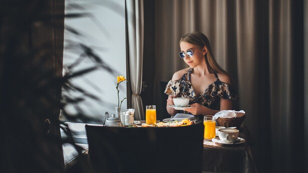 Ett matbord dukat för frukost, med ett glas apelsinjuice, en kopp kaffe och en tallrik med mat.