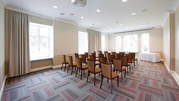 A conference room with rows of chairs, large windows, and a patterned carpet.