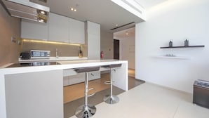 A modern kitchen with a central island, bar stools, and a minimalist design. - Piks Key - West Avenue (Dubai)