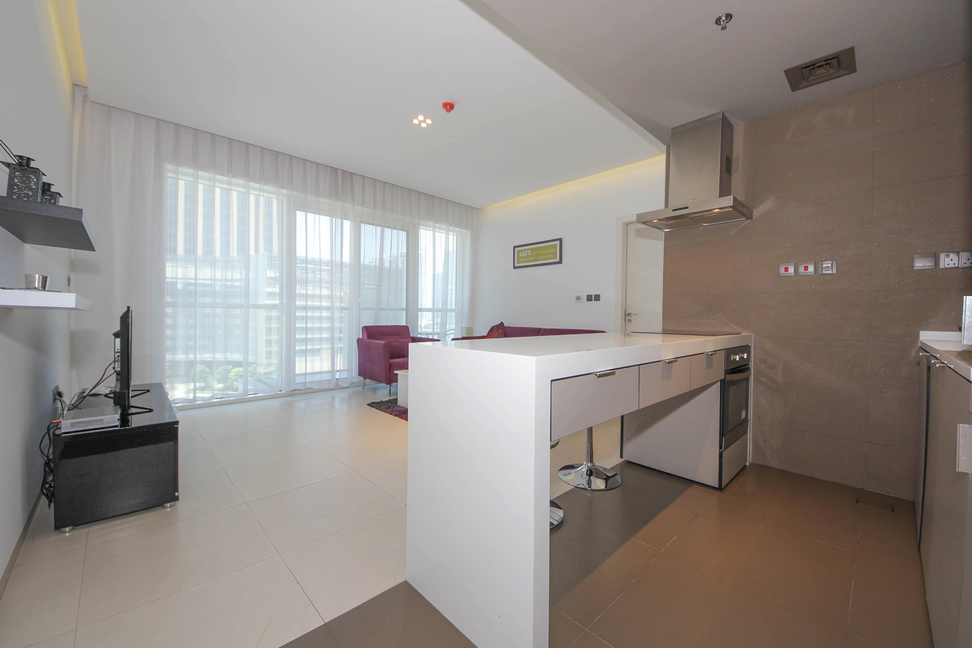 A modern kitchen with a white countertop, stainless steel appliances, and a large window providing natural light.
