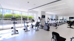 A modern gym with various cardio machines, large windows, and a clean, spacious layout. - Piks Key - West Avenue (Dubai)