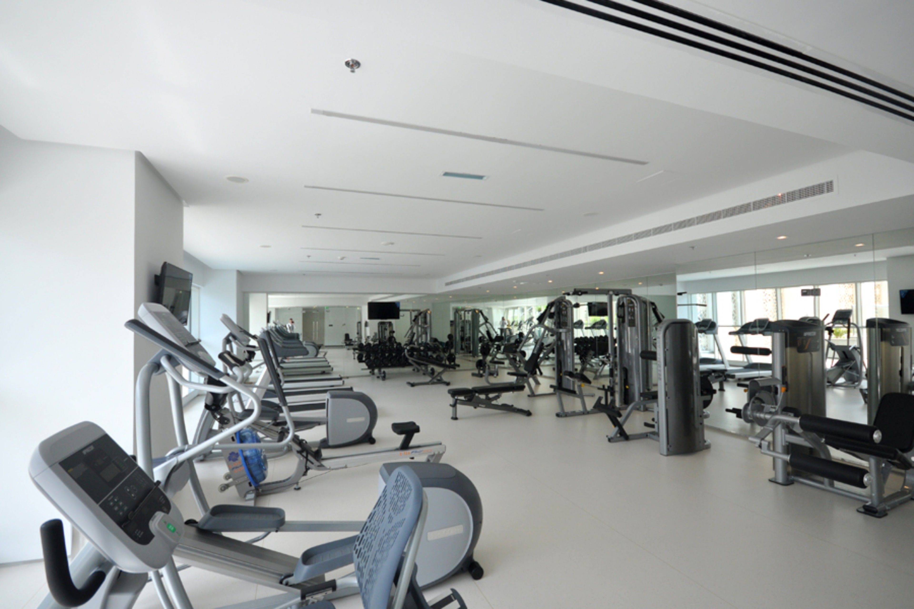 A modern gym with various exercise equipment, including treadmills, weight machines, and free weights.