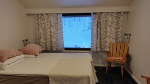Une chambre à coucher avec un lit, deux oreillers, une chaise et une fenêtre avec des rideaux.