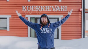 Une personne se tient devant un bâtiment sur lequel on peut lire l'inscription « KUERKIEVARI ».