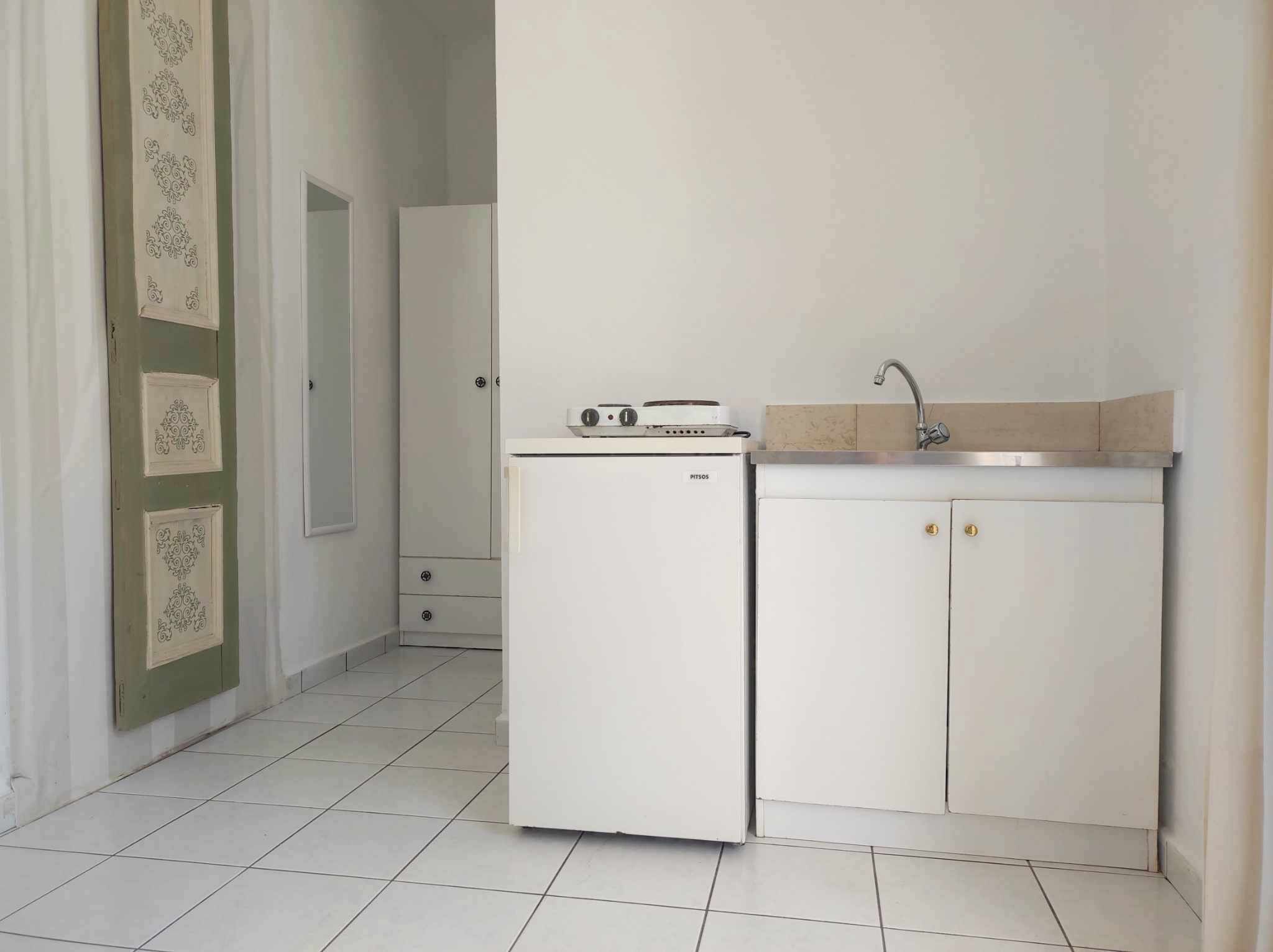 A compact kitchen with a refrigerator, a sink, and a cabinet.
