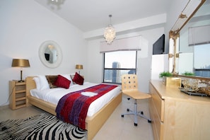 A modern bedroom with a large bed, a desk, a chair, a mirror, and a view of the city. - Piks Key - Bahar 1 (Dubai)