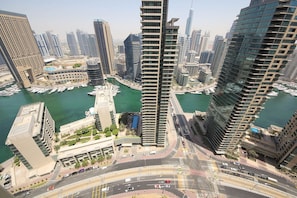 A high-rise building with a modern design, surrounded by other tall buildings and a marina with boats. - Piks Key - Bahar 1 (Dubai)