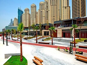 A modern urban plaza with benches, palm trees, and a red pathway. - Piks Key - Bahar 1 (Dubai)