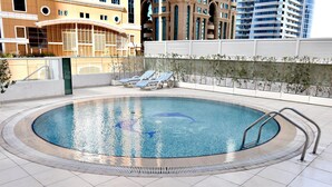 A rooftop pool with a circular shape, surrounded by a white tiled deck and a metal railing. - Piks Key- Marina Pinnacle (Dubai)