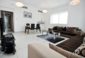 A modern living room with a sofa, coffee table, and dining area. - Piks Key- Marina Pinnacle (Dubai)