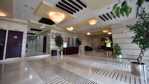 A spacious lobby with a modern design, featuring a reception desk, potted plants, and a large chandelier. - Piks Key- Marina Pinnacle (Dubai)