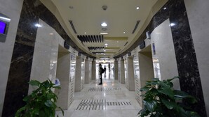 A corridor with marble walls, recessed lighting, and a central vent. - Piks Key- Marina Pinnacle (Dubai)